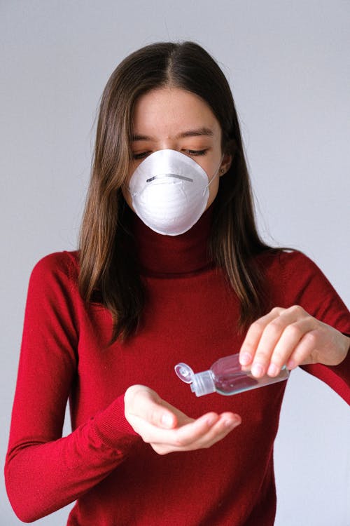 girl putting on hand sanitizer with mask. Education vs. Coronavirus